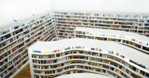 人物のいない明るい曲線書架の図書空間を背景に、ドルトン東京学園高等部の探究と転編入準備を考えるイメージ