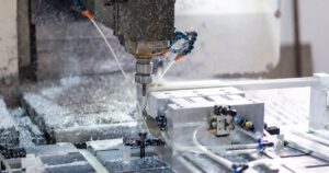 人物のいないCNC工作機械が金属を加工する様子を背景に、石巻工業高校の5学科と2027年度入試を考えるイメージ