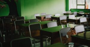 人物のいない教室の机と黒板を背景に、北見緑陵高校の2027年度入試と普通科単位制を考えるイメージ