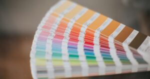 人物のいない実在のカラースウォッチを背景に、黒石高校情報デザイン科の商業・デザイン学習と2027年度入試を考えるイメージ