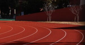 人物のいない赤い陸上トラックで前原高校の総合スポーツ・英語・文理コースと2027年度入試を考えるイメージ