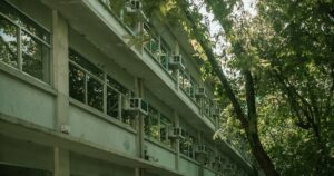 人物のいない学校建築と緑を写した横長写真。明光学園高校の2027年度共学化、4コース、入試日程を解説する記事のサムネイル