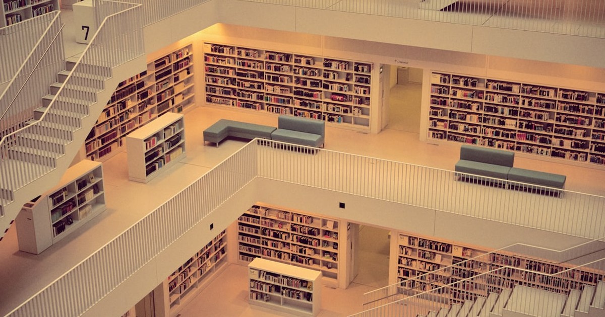人物のいない多層階の図書館に本棚と閲覧席が並ぶ、田奈高校閉校後の青葉総合高校と2027年度入試を考えるイメージ
