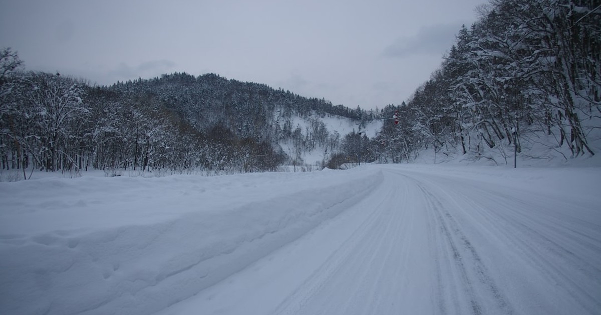 人物のいない雪原に一本の道が伸びる横長風景、横手高校の冬季通学と2027年度入試準備を考えるイメージ